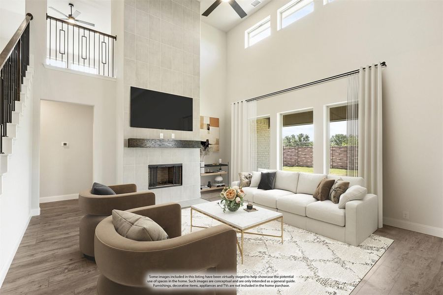 Living room with two-story ceiling, tile fireplace, hardwood floors, and large windows