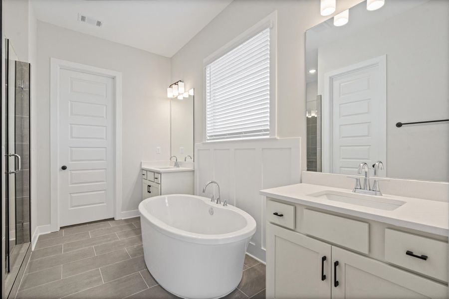 Spacious bathroom featuring a freestanding soaking tub, dual vanities with integrated sinks, and a glass-enclosed shower Spacious bathroom featuring a freestanding soaking tub, dual vanities with integrated sinks, and a glass-enclosed shower