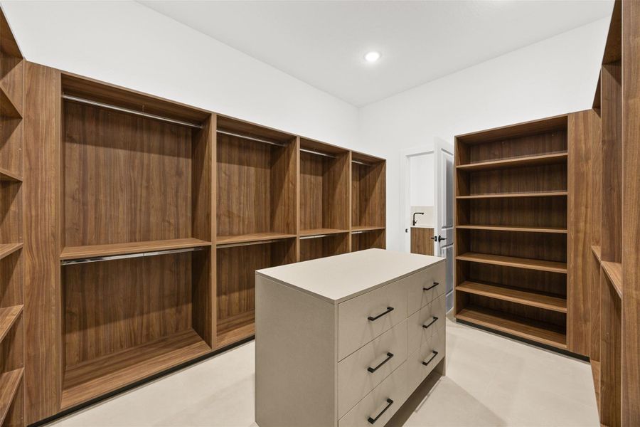Massive custom designed walk-in closet complete with center island, shelving, and wardrobe storage.