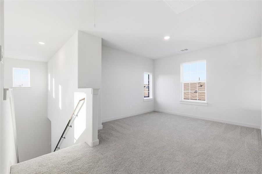 Carpeted loft area featuring recessed lighting and multiple windows Carpeted loft area featuring recessed lighting and multiple windows
