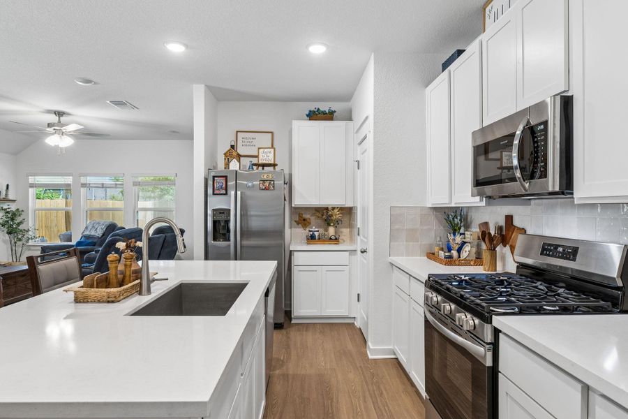 Modern kitchen featuring white cabinetry, stainless steel appliances, a gas range, a rectangular undermount sink, and light wood-finish flooring