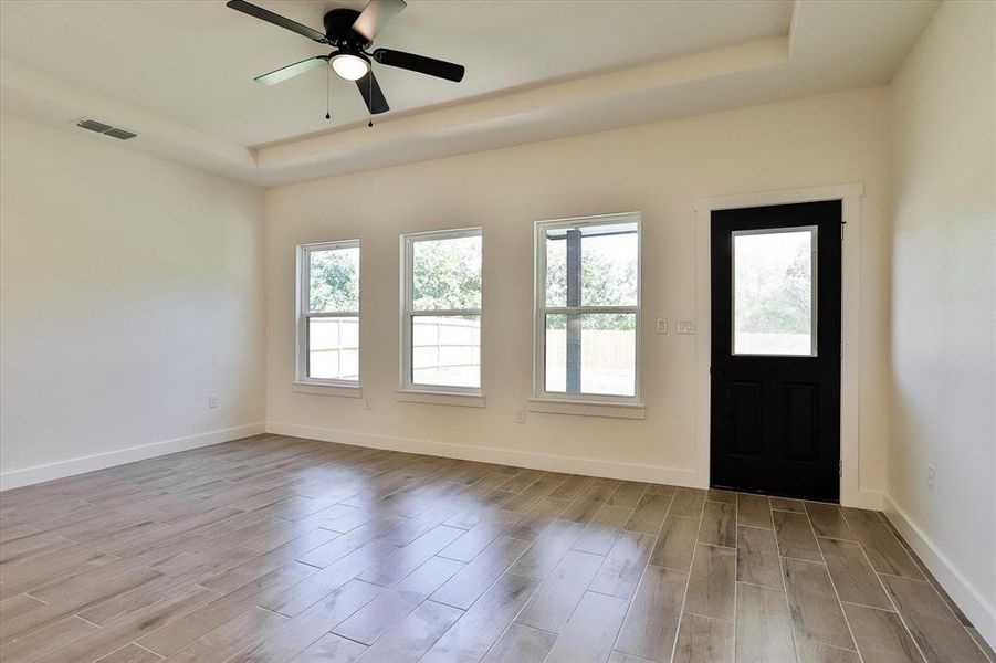 Foyer featuring a raised ceiling, light hardwood / wood-style flooring, and ceiling fan