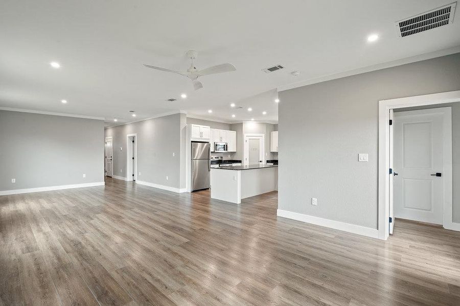 Unfurnished living room featuring recessed lighting, a ceiling fan, ornamental molding, and light wood-style flooring