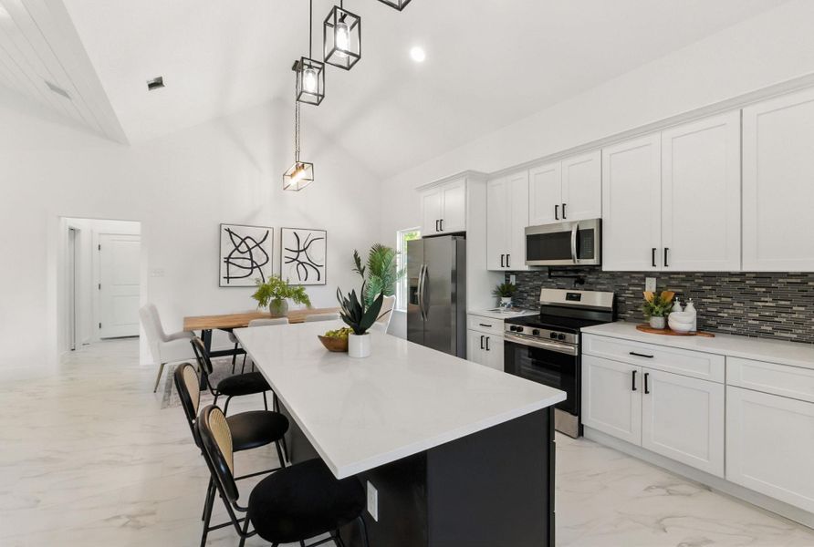 Kitchen with light tile finish floors, a breakfast bar, stainless steel appliances, and white cabinets