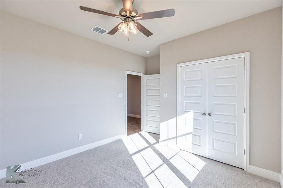 Unfurnished bedroom with light carpet, a ceiling fan, and a closet