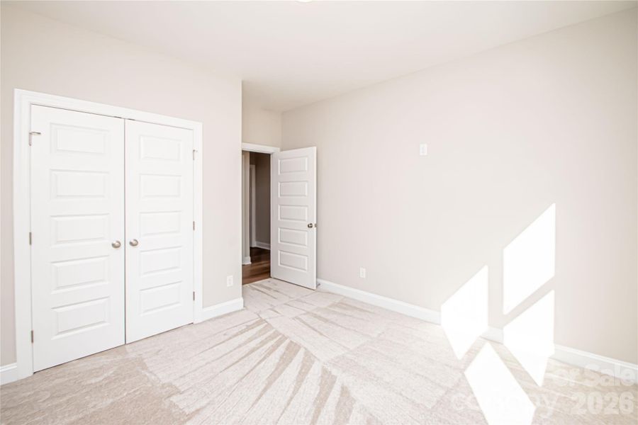 Spacious Bedroom #4 with plush carpet, large closet, oversized window, and convenient outlet ready for ceiling fan installation.