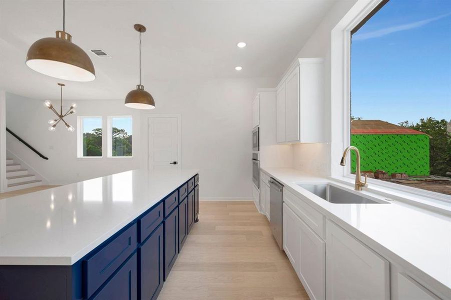 Kitchen featuring a spacious island with blue cabinetry, white countertops, and light wood-finish flooring