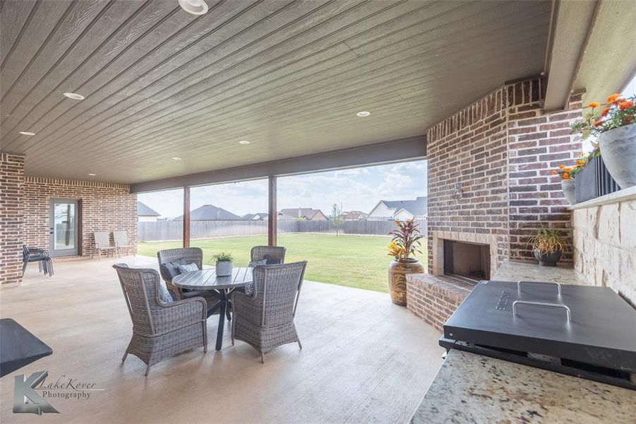 Fenced backyard featuring outdoor dining space, an outdoor brick fireplace, a patio area, and area for grilling Fenced backyard featuring outdoor dining space, an outdoor brick fireplace, a patio area, and area for grilling