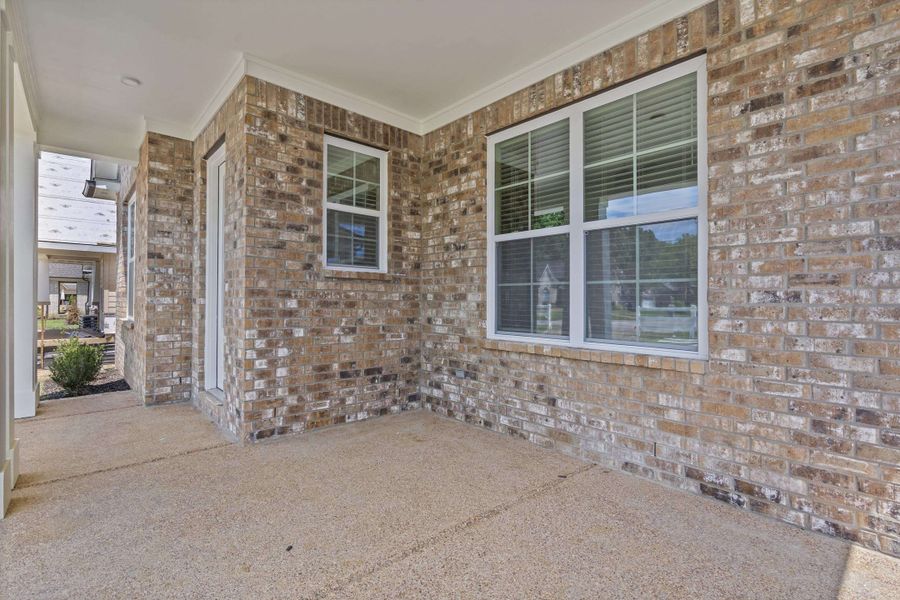 Spacious covered patio area featuring a brick exterior facade