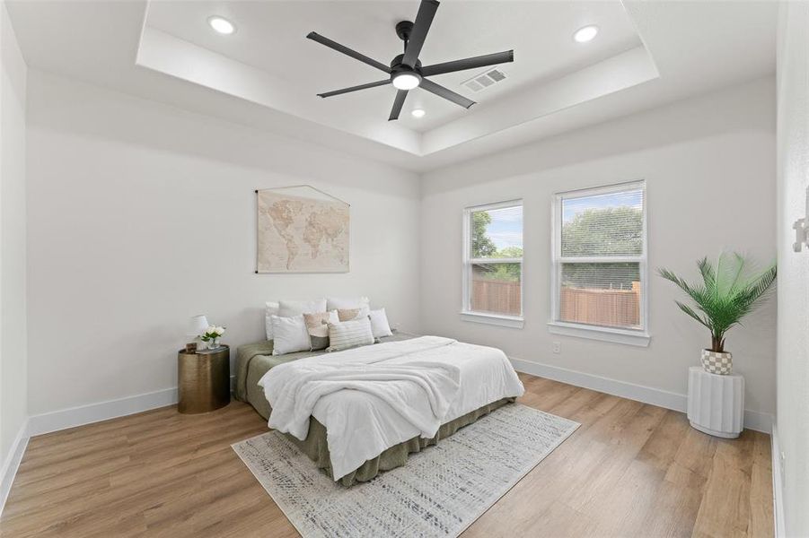 Bedroom with a tray ceiling, light wood-style flooring, recessed lighting, baseboards, and ceiling fan Bedroom with a tray ceiling, light wood-style flooring, recessed lighting, baseboards, and ceiling fan