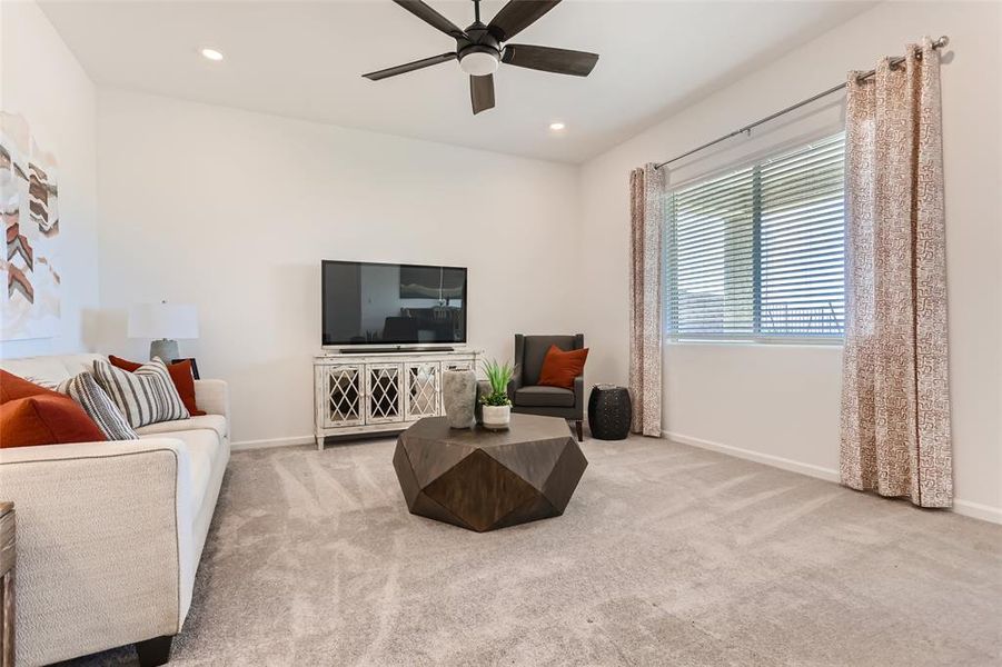 Carpeted living area with recessed lighting and a ceiling fan