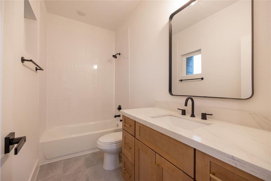 This stylish ensuite bath showcases elegant finishes throughout. A spacious vanity is lined with calacatta quartz with an under-mount sink and added storage is topped with gold hardware while the tub and shower combo is framed by classic white subway tiles, creating a clean and timeless look.