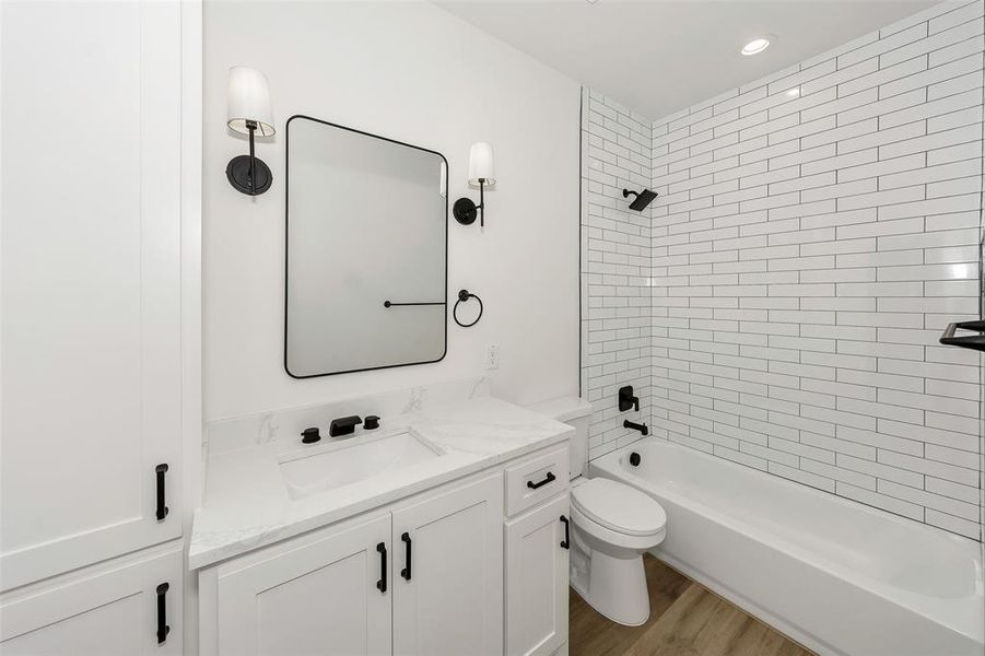 Bathroom with toilet, shower / bathtub combination, vanity, wood finished floors, and recessed lighting Bathroom with toilet, shower / bathtub combination, vanity, wood finished floors, and recessed lighting