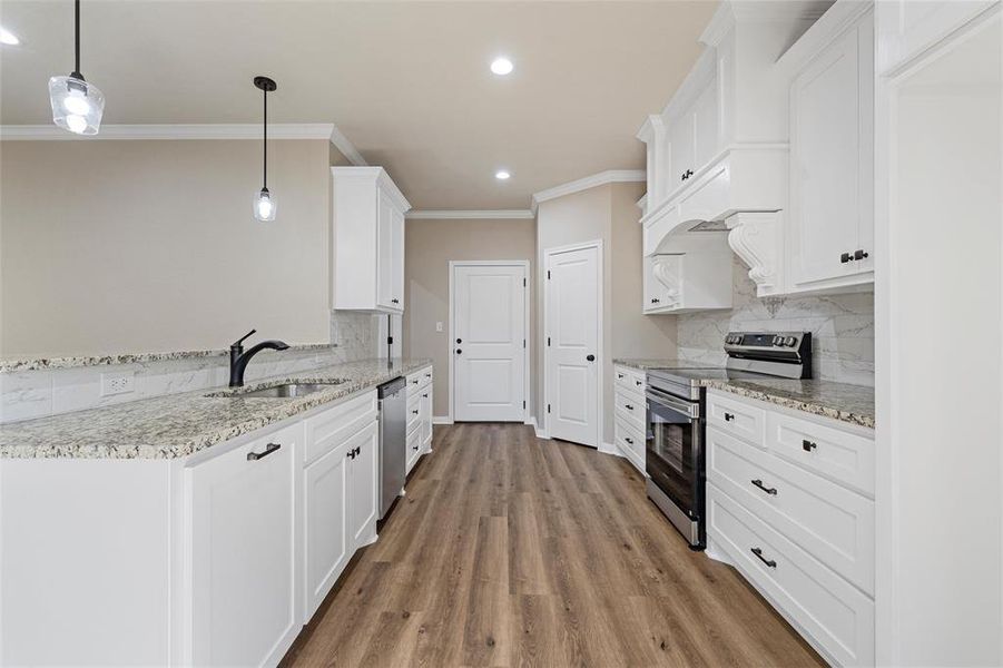 Kitchen featuring appliances with stainless steel finishes, crown molding, decorative backsplash, recessed lighting, and white cabinets