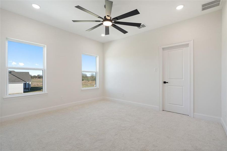 Carpeted spare room featuring ceiling fan and a healthy amount of sunlight