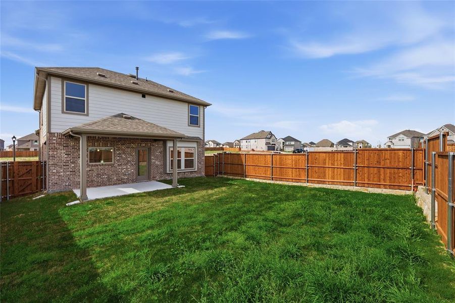 Expansive backyard featuring a covered patio, privacy fencing, and a combination brick and siding exterior
