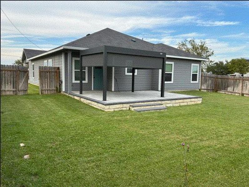 Back of property featuring a patio and a fenced backyard with beautiful St Augustine grass.