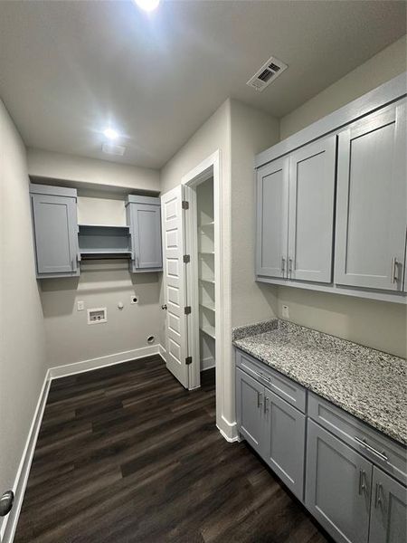 Kitchen with gray cabinets, light stone counters, and dark hardwood / wood-style flooring