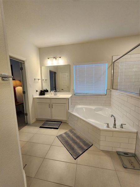 Indulge in relaxation within this primary bathroom featuring a corner soaking tub and spacious vanity.
