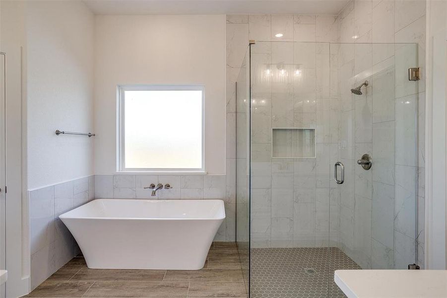 Bathroom featuring tile walls and shower with separate bathtub