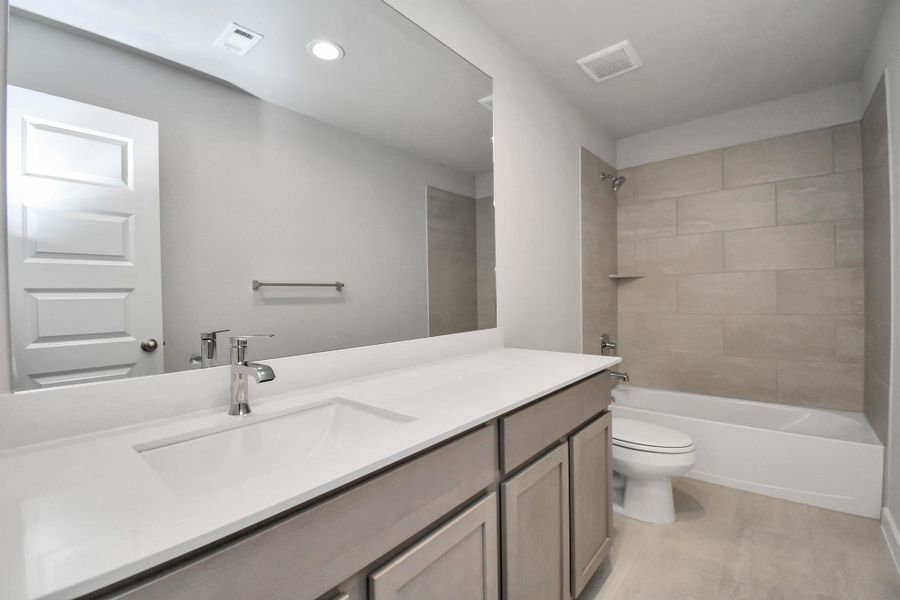 Secondary bath features tile flooring, bath/shower combo with tile surround, light stained wood cabinets, beautiful light countertop. Secondary bath features tile flooring, bath/shower combo with tile surround, light stained wood cabinets, beautiful light countertop.