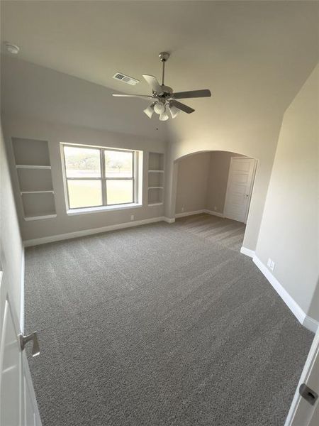 Spare room featuring carpet flooring, built in features, and ceiling fan