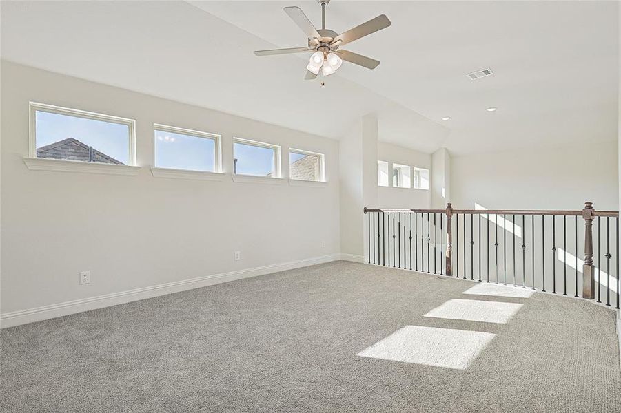 Unfurnished room with carpet flooring, ceiling fan, a wealth of natural light, and vaulted ceiling