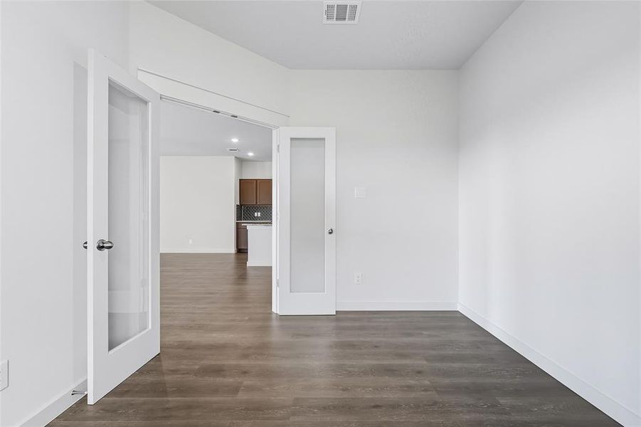 Empty room with dark wood-style floors, recessed lighting, and french doors Empty room with dark wood-style floors, recessed lighting, and french doors