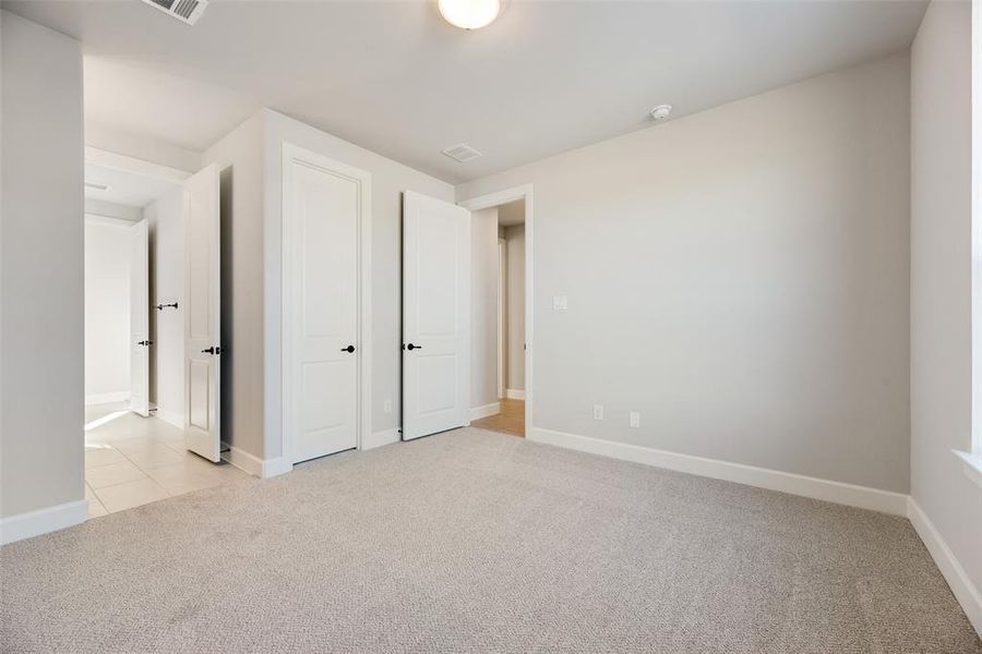 Unfurnished bedroom featuring light carpet and baseboards Unfurnished bedroom featuring light carpet and baseboards