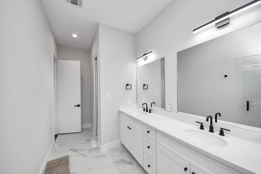 Spacious primary bathroom featuring dual vanities and designer finishes