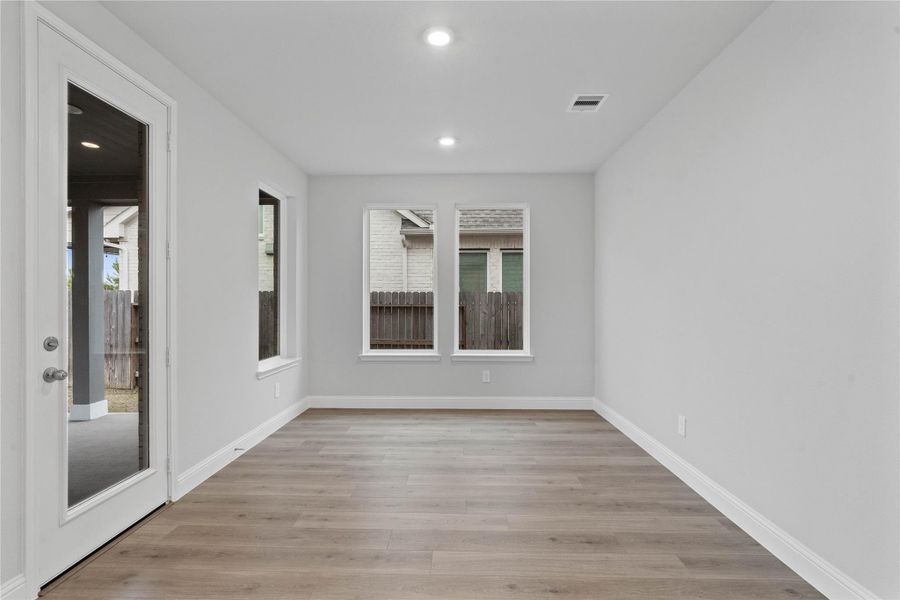 The breakfast room is filled with natural light and features high ceilings, recessed lighting, expansive windows with fitted blinds, and an access door to the back covered patio.