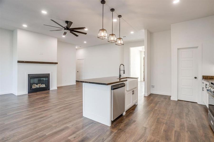 Kitchen featuring white cabinetry, ceiling fan, hanging light fixtures, a kitchen island with sink, and appliances with stainless steel finishes