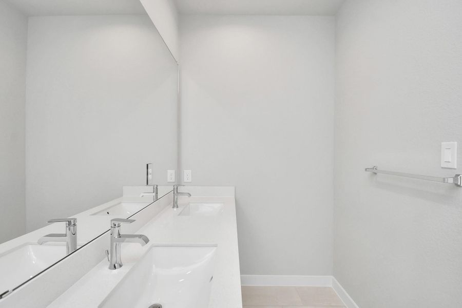 Elevate your daily routine at the elegant vanity, now equipped with double sinks, light countertops, modern hardware, and beautiful recessed lights. Sample photo of completed home with similar floor plan. Actual colors and selections may vary.