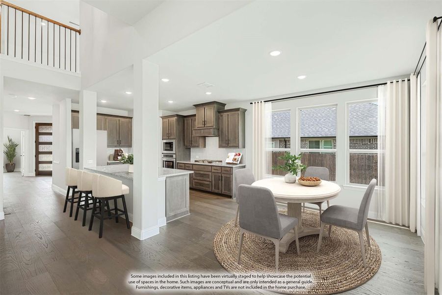 Open-plan dining area and kitchen with round table, gray cabinets, kitchen island, and hardwood floors under high ceilings Open-plan dining area and kitchen with round table, gray cabinets, kitchen island, and hardwood floors under high ceilings