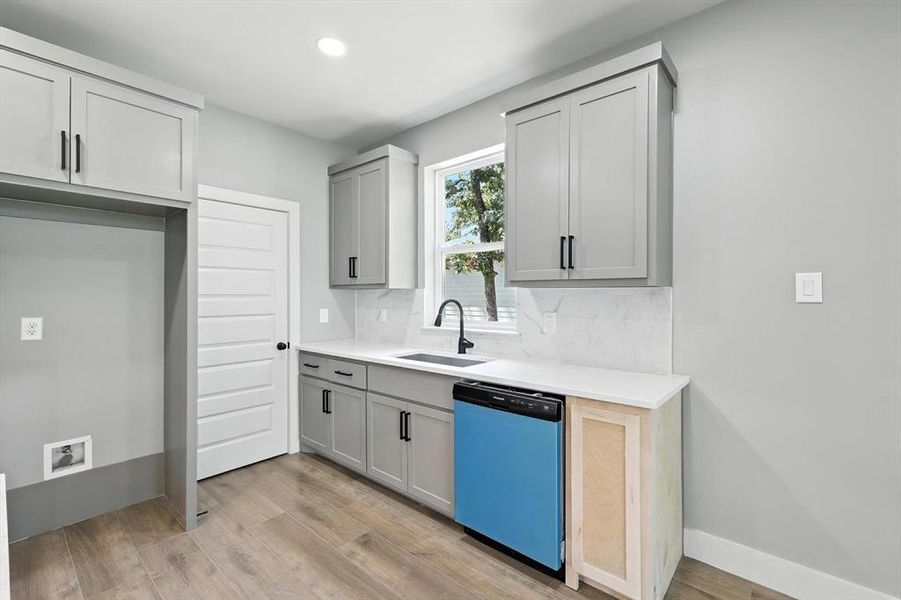 Kitchen with dishwasher, light wood-style floors, backsplash, recessed lighting, and light stone counters