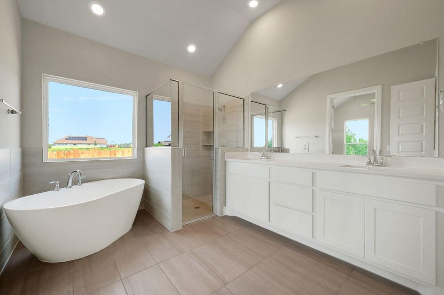 Full bath featuring a shower stall, lofted ceiling, double vanity, a freestanding bath, and recessed lighting Full bath featuring a shower stall, lofted ceiling, double vanity, a freestanding bath, and recessed lighting