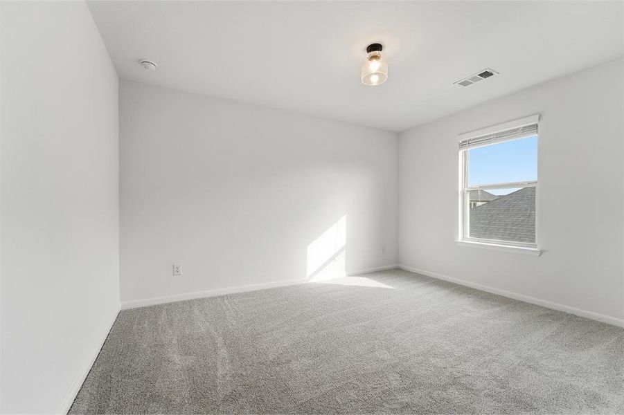 Spacious room with light gray carpeting, neutral wall paint, and a single window