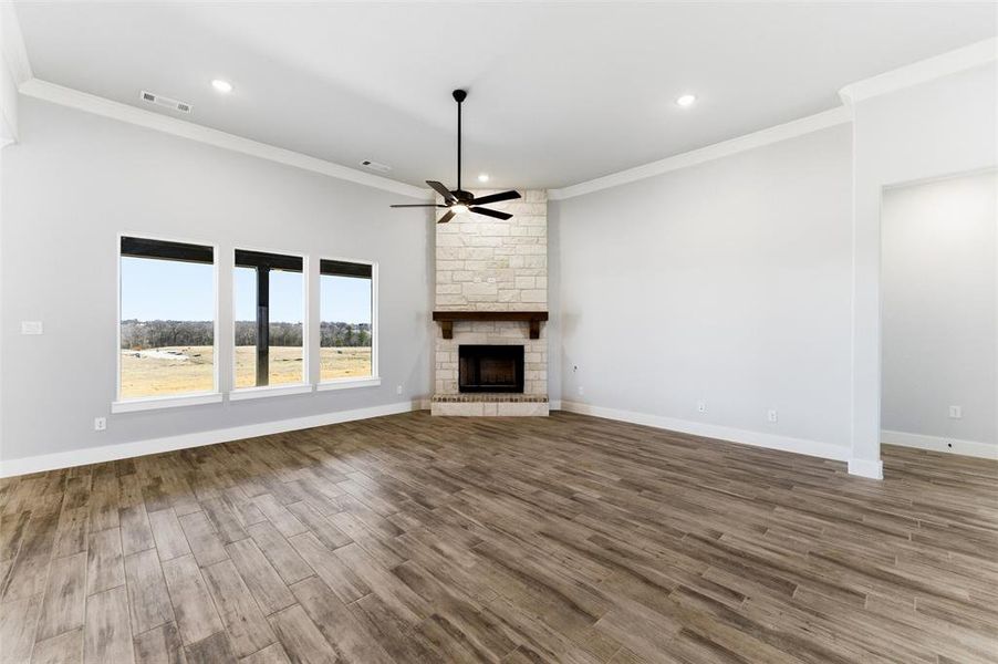 Unfurnished living room featuring ceiling fan, recessed lighting, a fireplace, crown molding, and wood finished floors