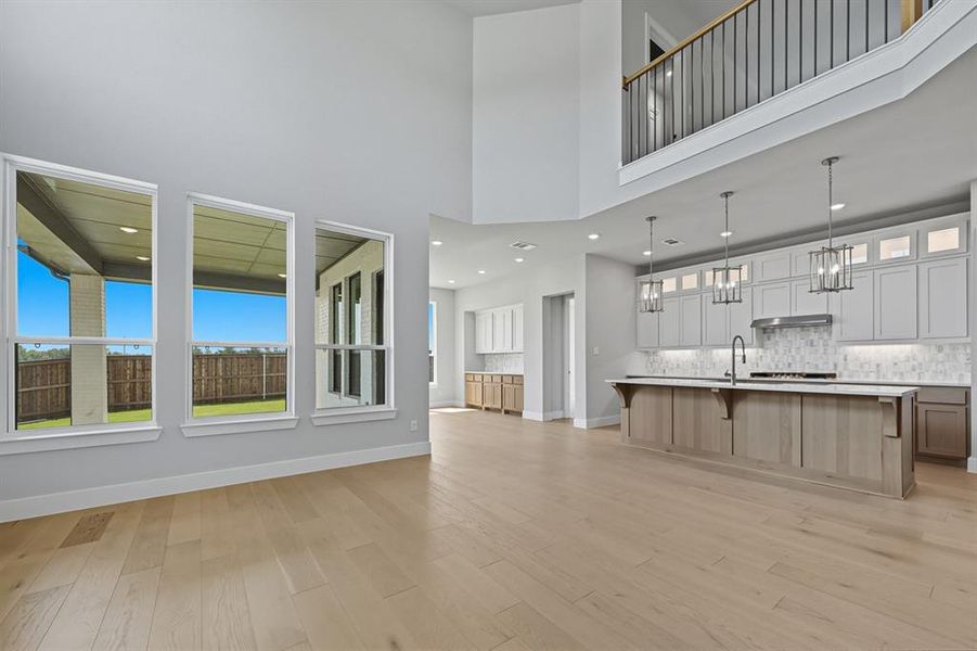 Unfurnished living room with a towering ceiling, light wood-style flooring, and recessed lighting