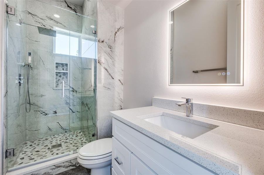 Bathroom with vanity, toilet, and a shower with shower door