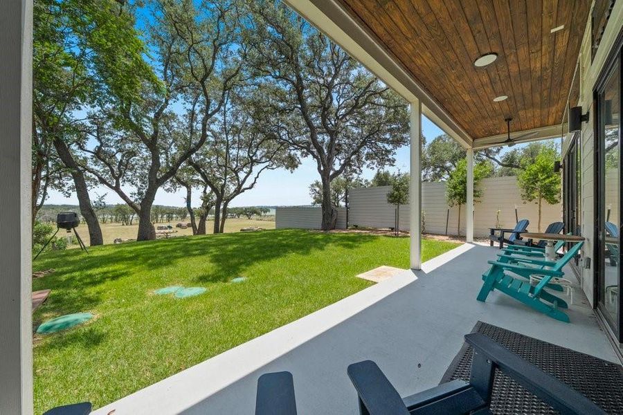 Relax beneath the expansive covered patio where wood-plank ceilings, ceiling fans, and uninterrupted views of the surrounding landscape create the perfect outdoor living space for every season. Relax beneath the expansive covered patio where wood-plank ceilings, ceiling fans, and uninterrupted views of the surrounding landscape create the perfect outdoor living space for every season.