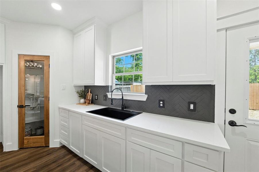 Kitchen with backsplash, dark wood-type flooring, healthy amount of natural light, white cabinets, and recessed lighting