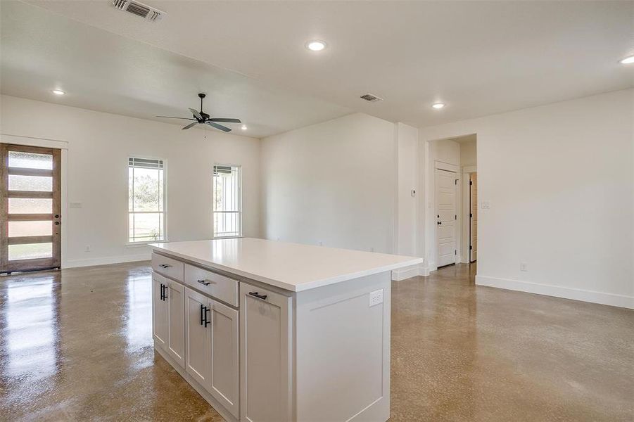 Kitchen with white cabinets, ceiling fan, and a kitchen island