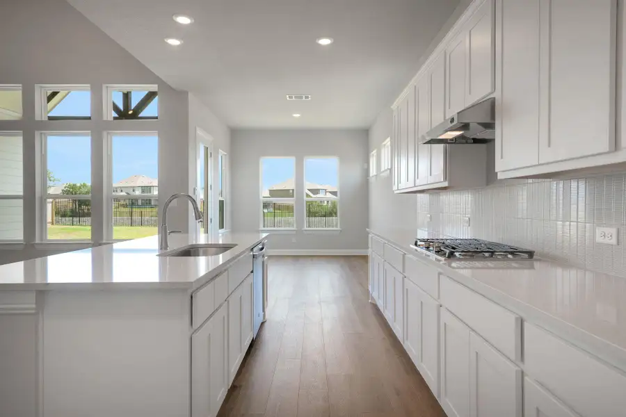 Kitchen featuring white cabinetry, recessed lighting, light wood-style floors, light stone countertops, and a center island with sink