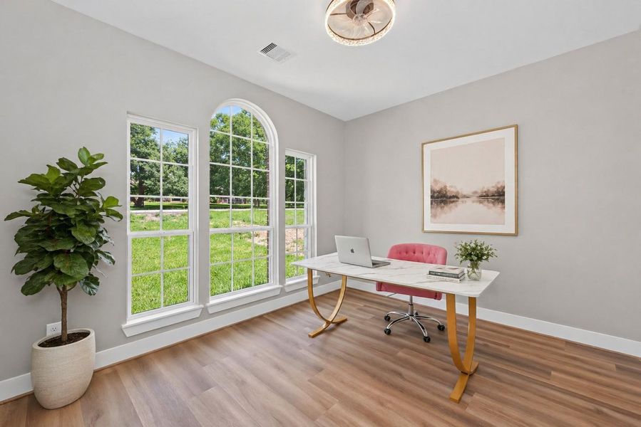 Bright home office with large arched windows offering plenty of natural light, perfect for remote work or study.