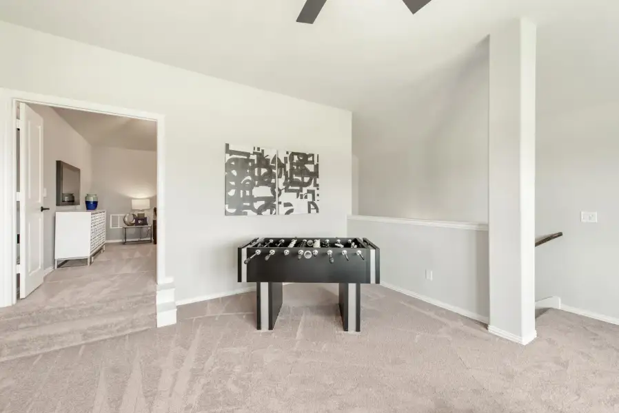 Bonus room with foosball table, carpet flooring, vaulted ceiling, and ceiling fan