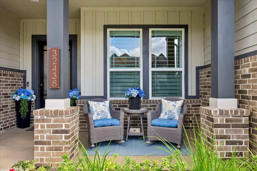 Covered front porch framed by painted Hardy siding and brick creates a warm architectural entry with clean lines and recessed lighting overhead. Glass pane mahogany front door allows natural light inside while maintaining a sence of privacy.