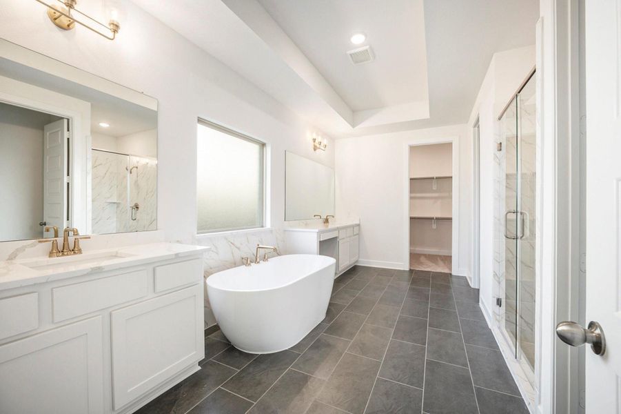 The luxury primary bath offers a spa-like retreat featuring a separate soaking tub and glass-enclosed shower. Designed with relaxation in mind, this elegant space combines high-end finishes, sleek fixtures, and refined details, creating the perfect balance of comfort and sophistication.