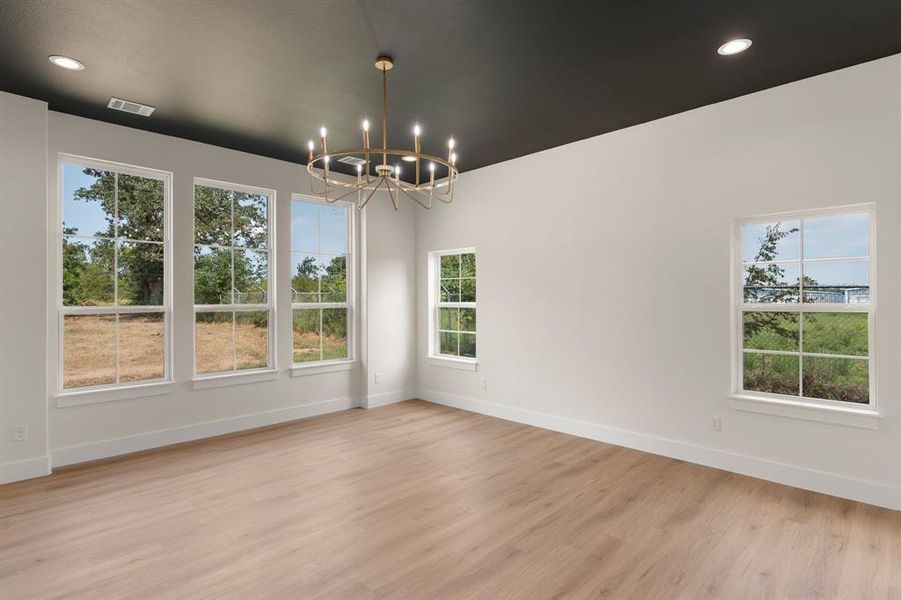 Unfurnished dining area featuring a chandelier, light wood-style floors, plenty of natural light, and recessed lighting