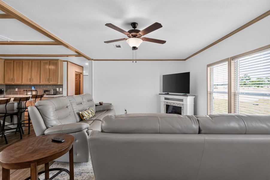 A comfortable living area features a decorative fireplace, large windows, and an adjacent kitchen bar.